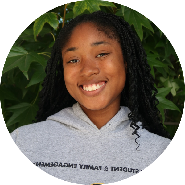 Woman smiling with grey sweatshirt in front of leaves